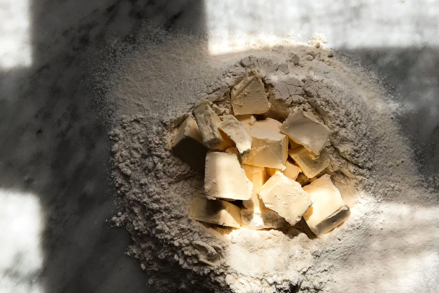 Burro a pezzi su un mucchio di farina, ingredienti per la sabbiatura della pasta frolla